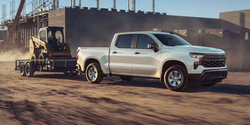 2026 Chevy Silverado 1500 navigating a snow-covered road in Imlay City, MI, highlighting its four-wheel-drive capability, ground clearance, and winter-ready truck design